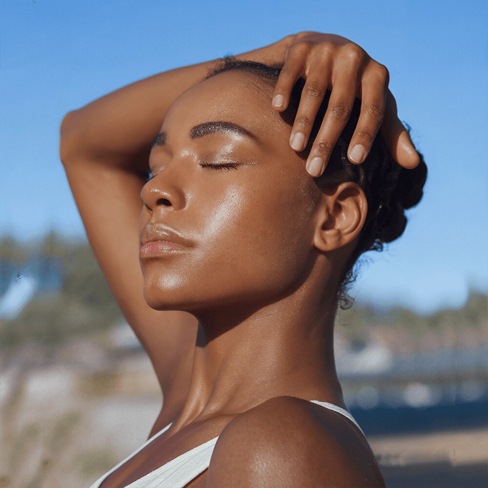 Woman enjoying a sunlit skincare ritual outdoors