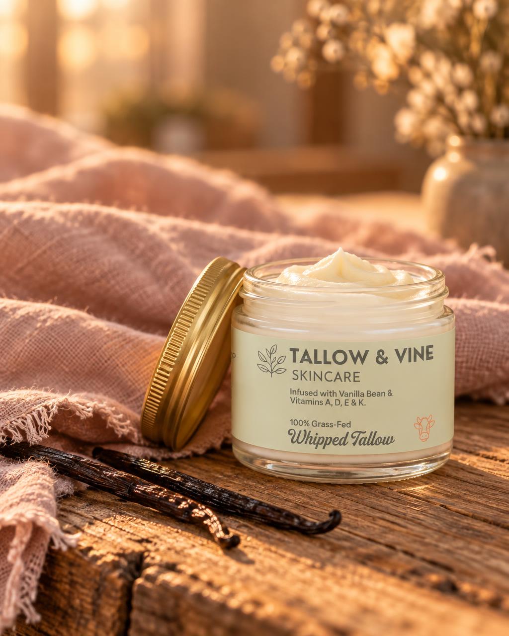 100% Grass-Fed Whipped Vanilla Bean Tallow Balm open jar with gold lid on warm wood and blush linen with vanilla bean pods